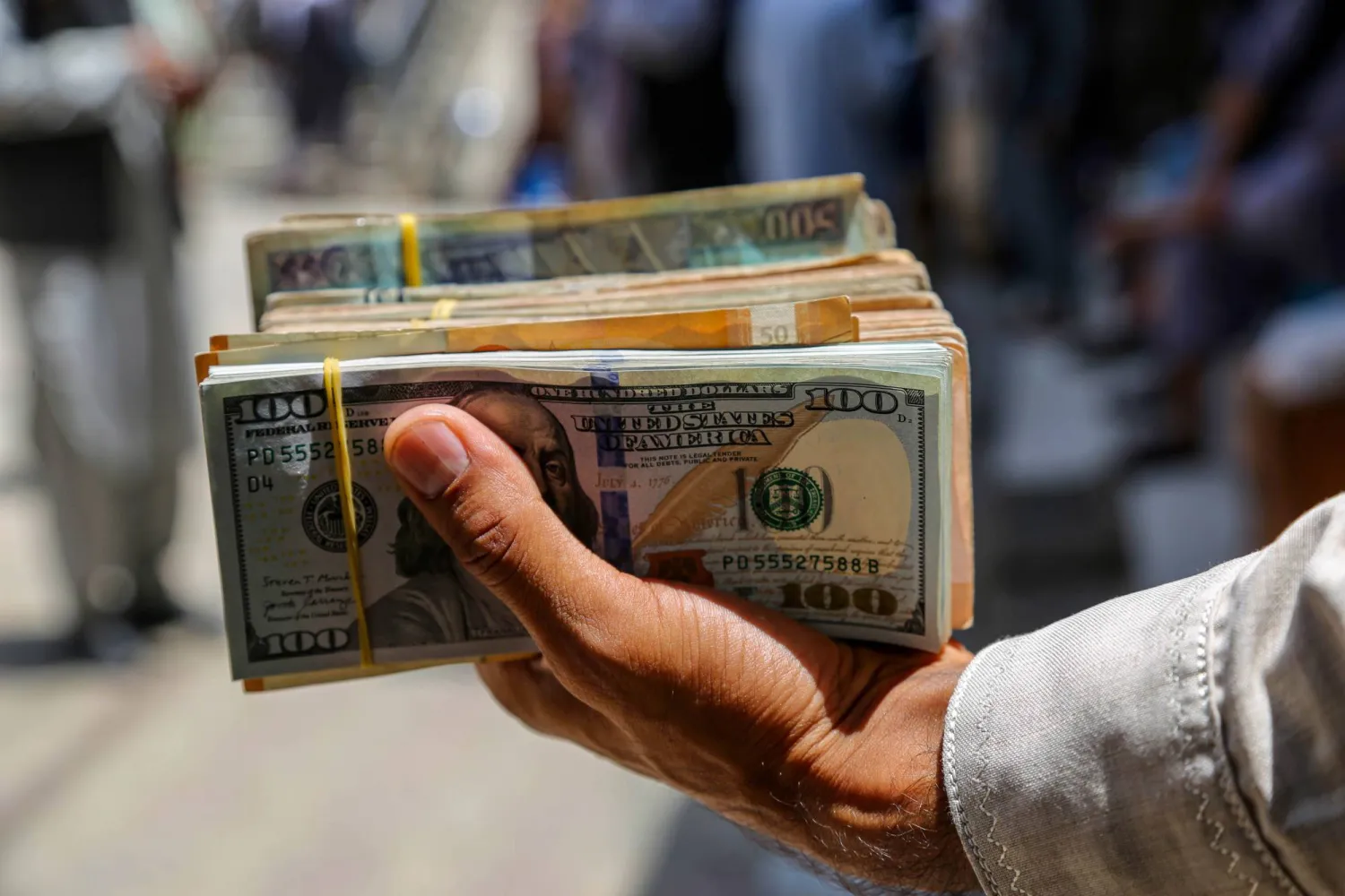رجل يحمل أوراقاً نقدية من الدولار (إ.ب.أ)