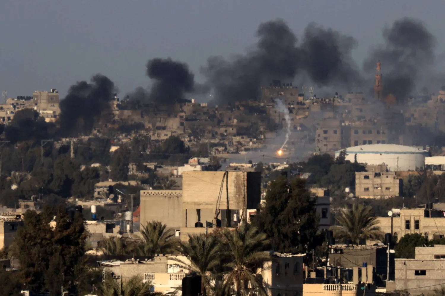 This photograph taken on January 15, 2024 from Rafah shows a flare and smoke billowing over Khan Yunis in the southern Gaza Strip during Israeli bombardment, amid ongoing battles between Israel and the Palestinian group Hamas. (Photo by AFP)