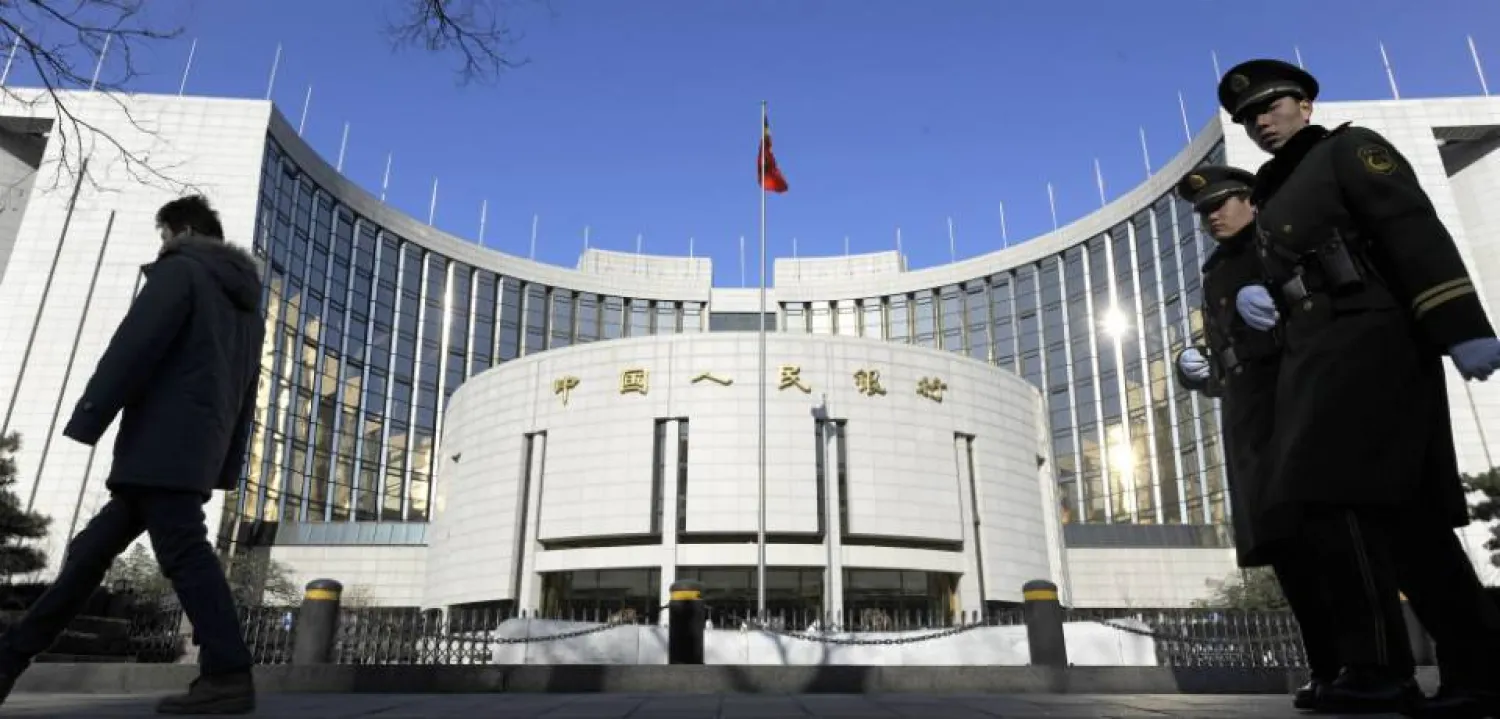 مشاة أمام مقر «بنك الشعب» الصيني المركزي في العاصمة بكين (أ.ف.ب)