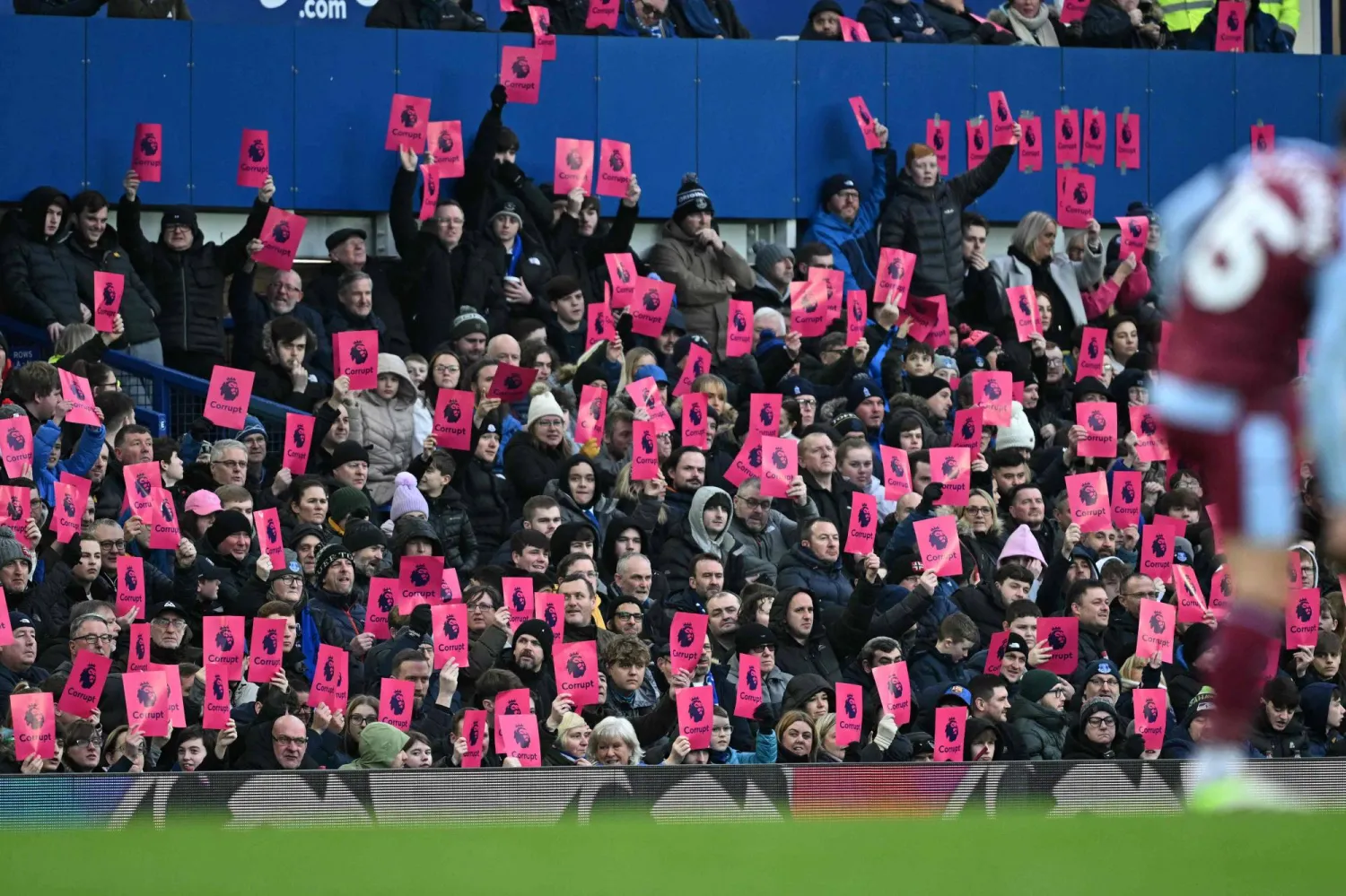 جماهير إيفرتون ترفع بطاقات وردية لامعة تحمل شعار «الأسد» للدوري الإنجليزي الممتاز وكلمة «فاسد» (أ.ف.ب)