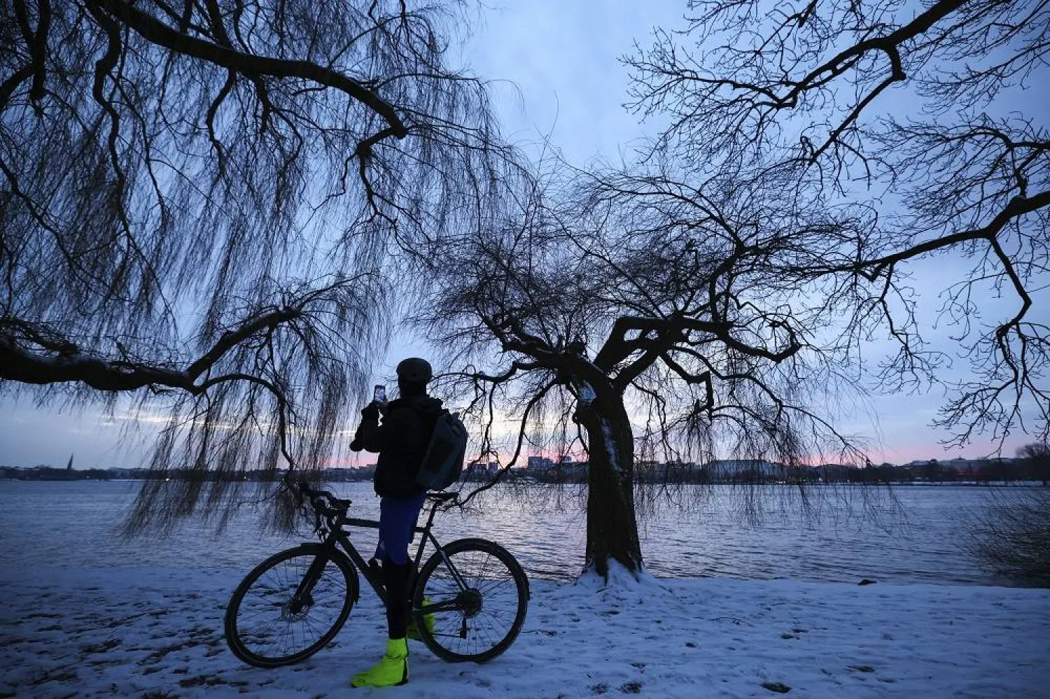 A cyclist takes pictures on a wintry morning on the Outer Alster, in Hamburg, Germany, Wednesday, Jan. 17, 2024. (AP)