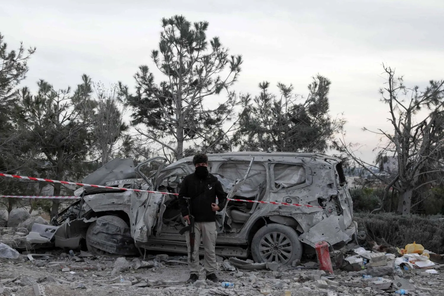 Bir güvenlik görevlisi, İran’ın pazartesi gecesi Erbil’de bir evi vurması sonucu tahrip olan bir arabayı inceliyor (AFP)