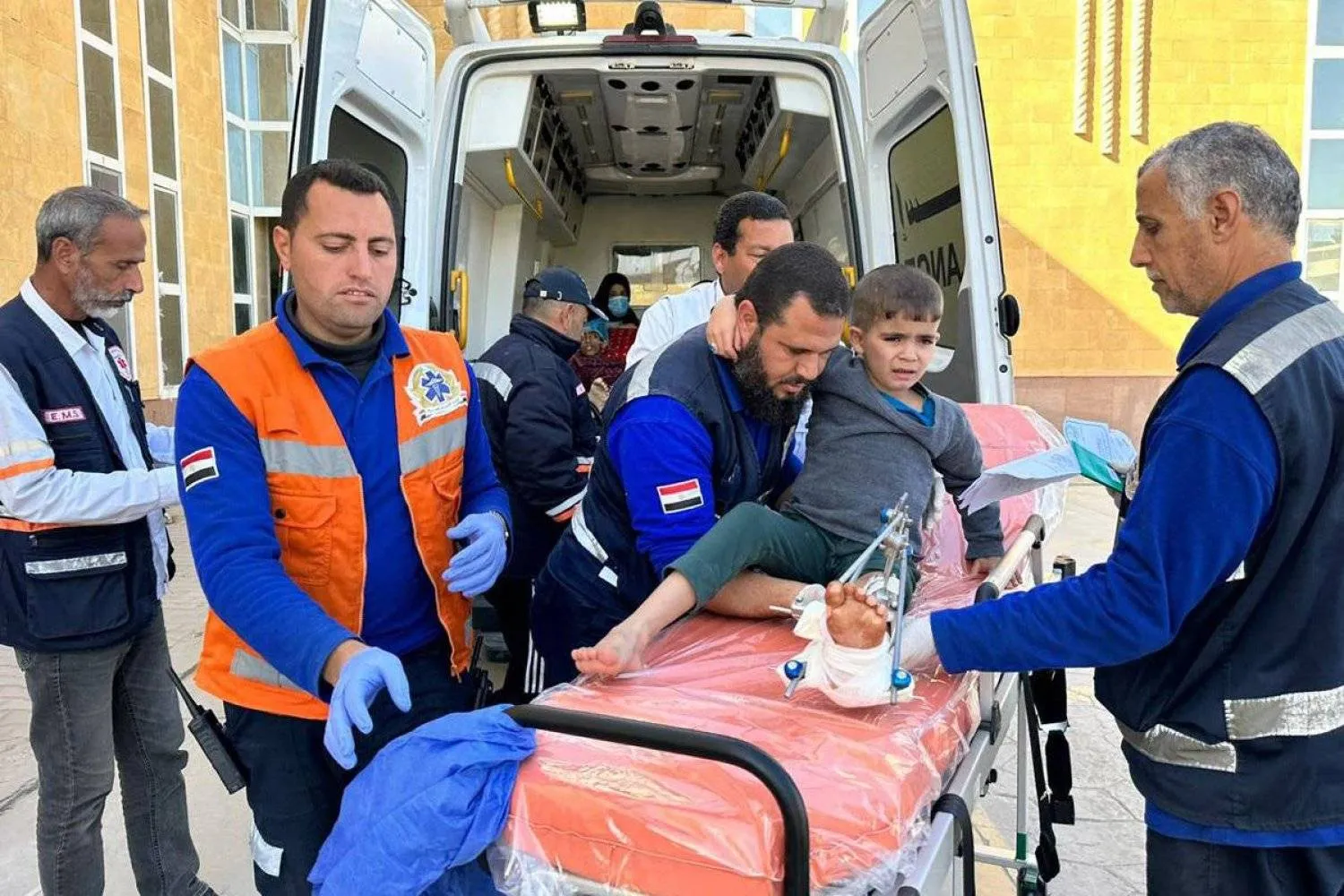 مسعفون مصريون يستقبلون طفلاً فلسطينياً مصاباً عبر معبر رفح الحدودي مع غزة (أ.ف.ب)