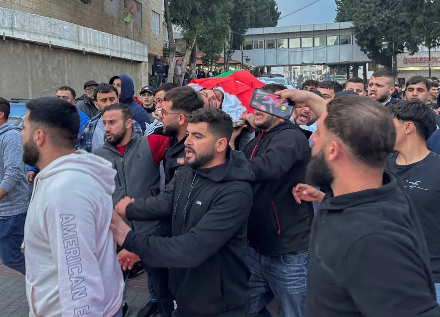 فلسطينيون يحملون جثمان الشاب الأميركي الفلسطيني البالغ من العمر 17 عاما الذي قتل برصاص إسرائيلي في رام الله (رويترز)