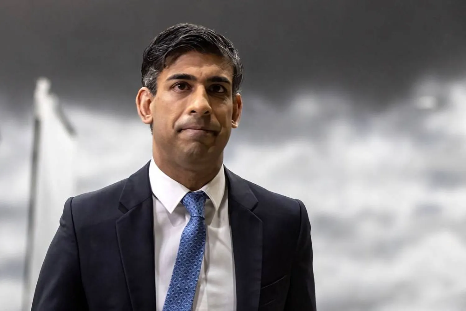 Britain's Prime Minister Rishi Sunak reacts after giving an interview to a TV journalist, standing in front of a back drop of a stormy sky, painted by students in a film studio, during his visit to the National Film and Television School in Beaconsfield on January 22, 2024. (AFP)