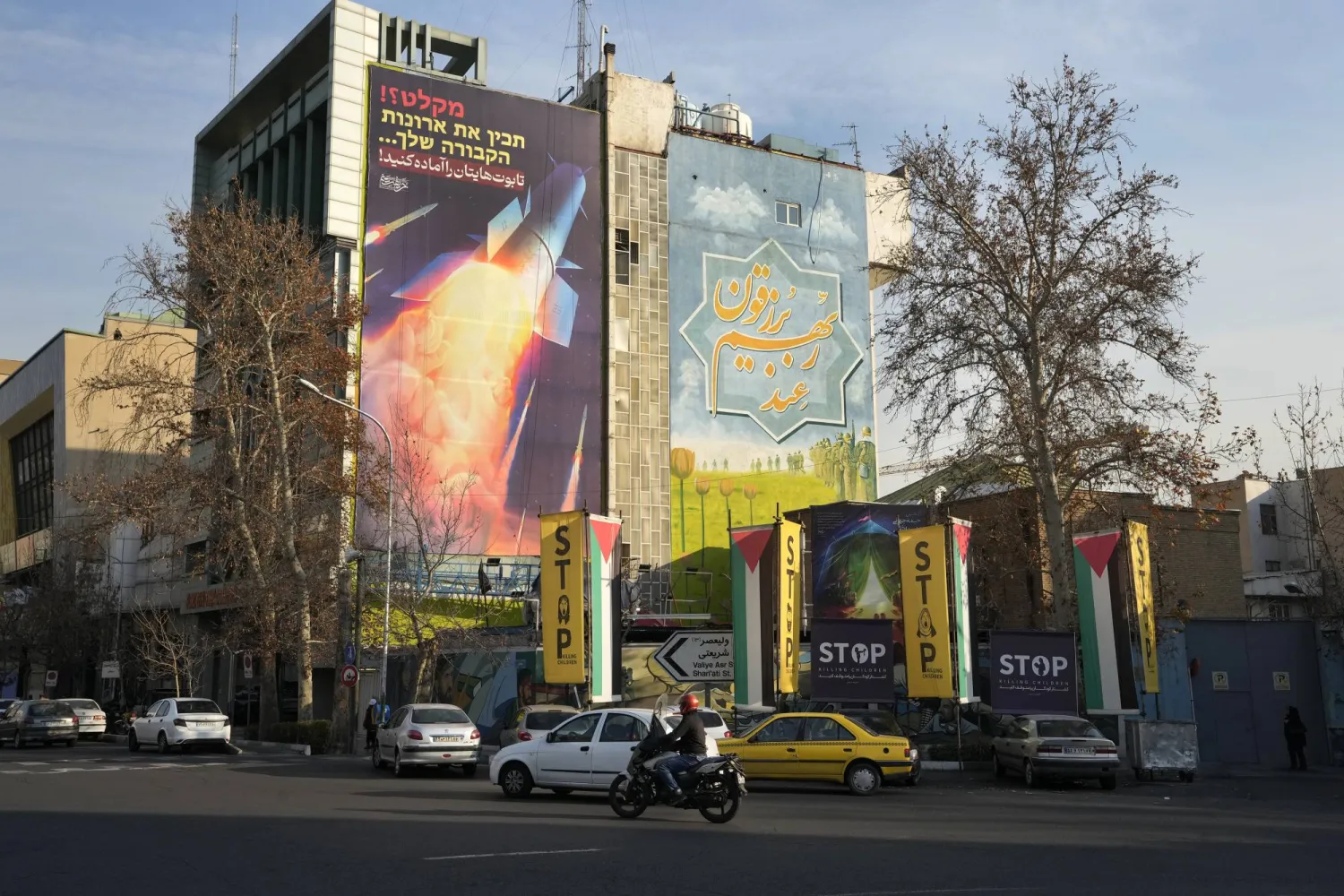 Vehicles drive past an anti-Israeli mural showing a launched missile with sign in Farsi reading "Death to America", at the Felestin (Palestine) Sq. in downtown Tehran, Iran, Thursday, Jan. 18, 2024. The sign on top reads in Farsi and Hebrew: "Prepare your coffins". (AP Photo/Vahid Salemi)