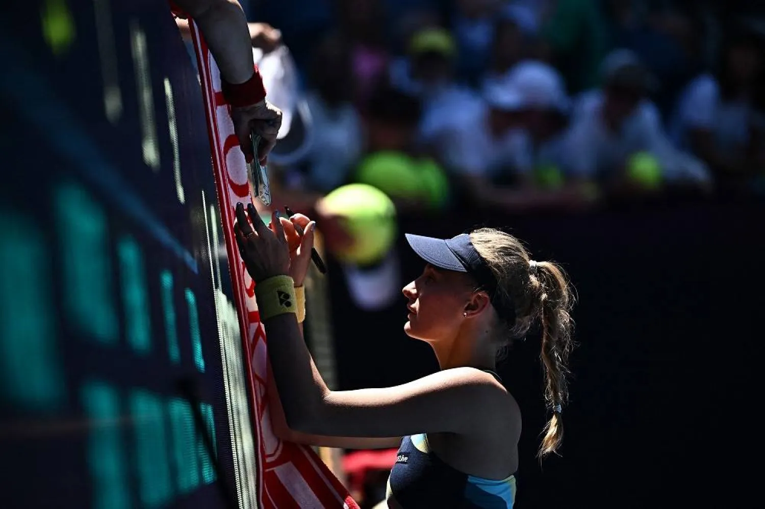 Ukraine's Dayana Yastremska signs autographs as she leaves the court after victory against Czech Republic's Linda Noskova in their women's singles quarter-final match on day 11 of the Australian Open tennis tournament in Melbourne on January 24, 2024. (AFP)