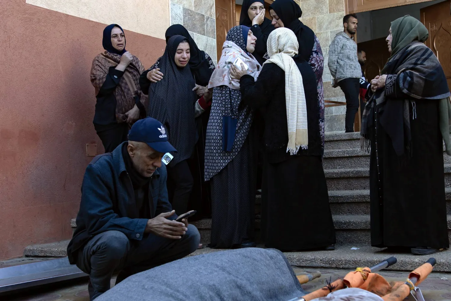 أقارب فلسطينيون من عائلة واحدة قُتلوا خلال غارة جوية إسرائيلية استهدفت منزلهم في خان يونس يبكون أمام جثثهم الملفوفة خارج مستشفى ناصر (إ.ب.أ)