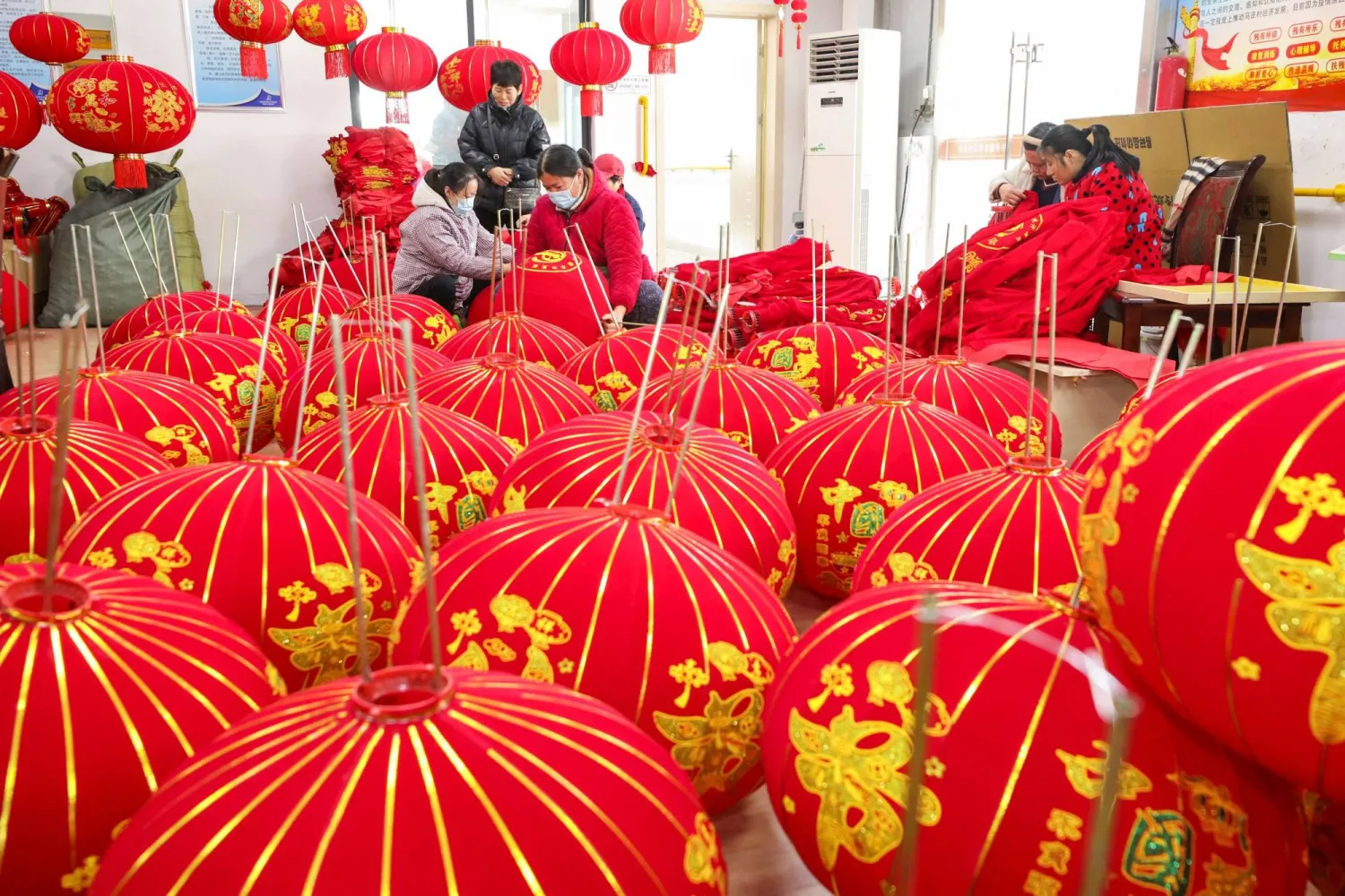 صينيون يقومون بإعداد الزينة التقليدية لاحتفال السنة القمرية في شرق البلاد (أ.ف.ب)