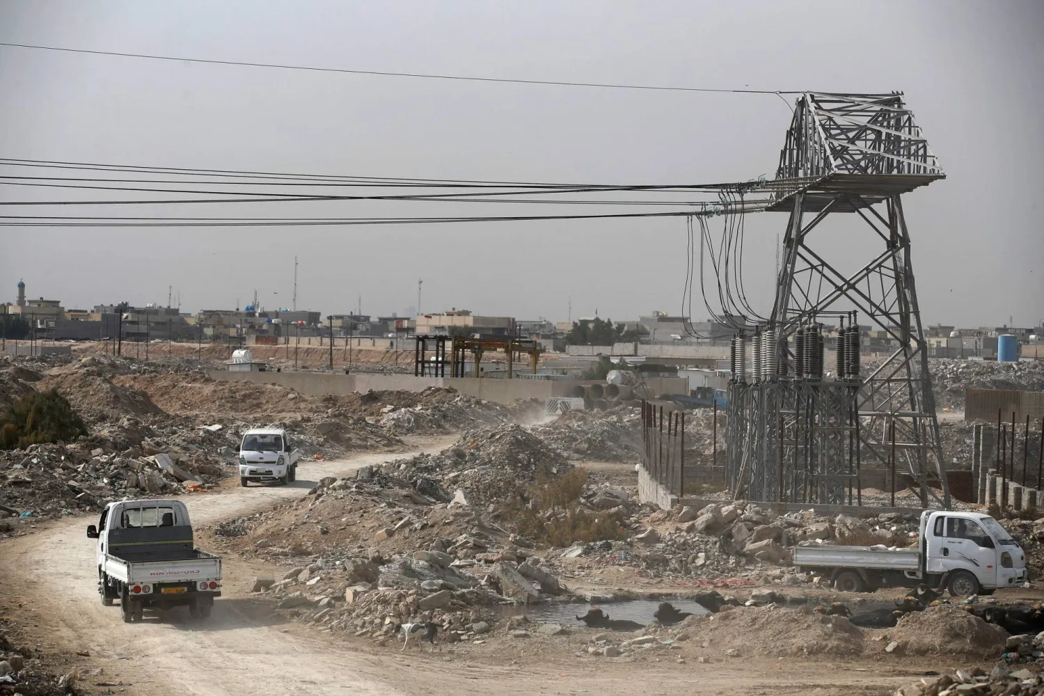 This photograph taken on January 21, 2024 shows vehicles driving under electricity wires in al-Fadiliya, east of Baghdad. (Photo by AHMAD AL-RUBAYE / AFP)