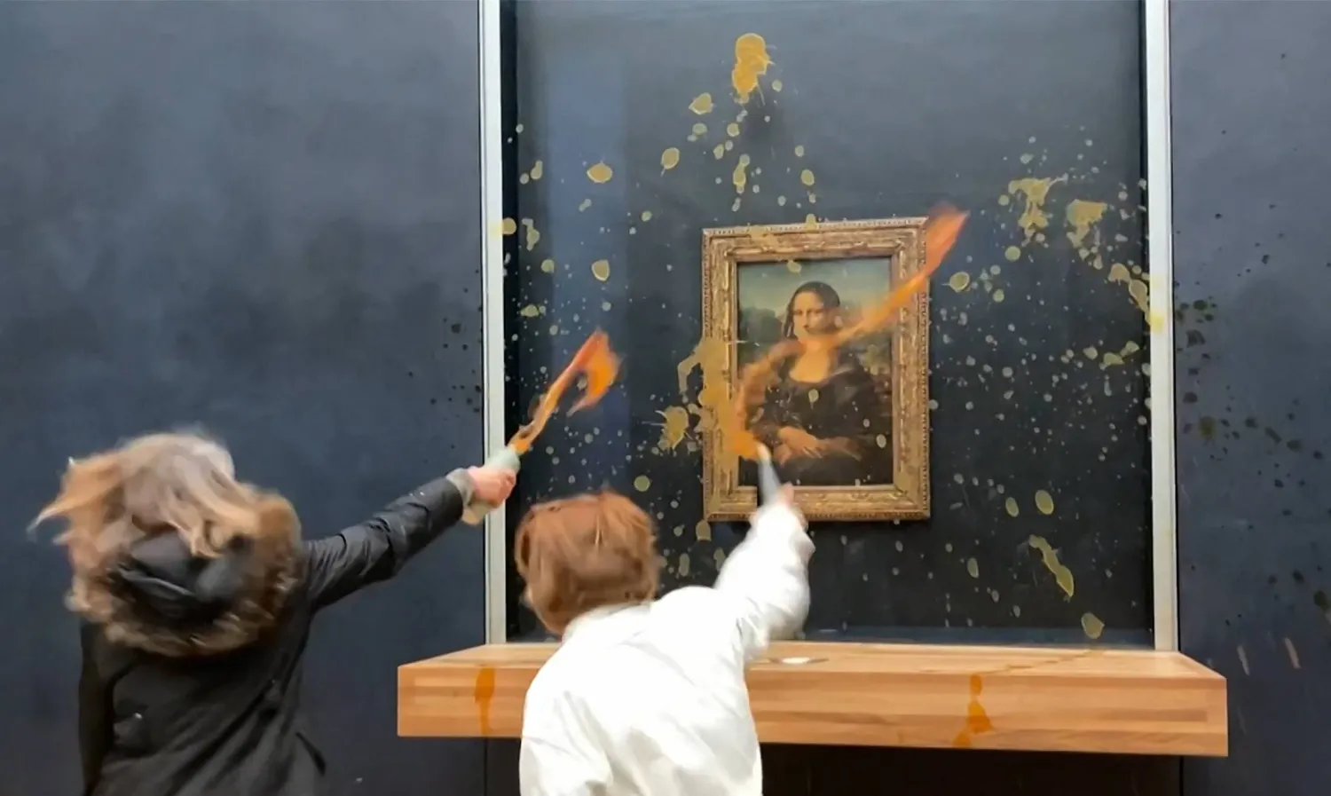 This image grab taken from AFPTV footage shows two environmental activists from the collective dubbed "Riposte Alimentaire" hurling soup at Leonardo Da Vinci's "Mona Lisa" painting, at the Louvre museum in Paris, on January 28, 2024. (Photo by David CANTINIAUX / AFPTV / AFP)