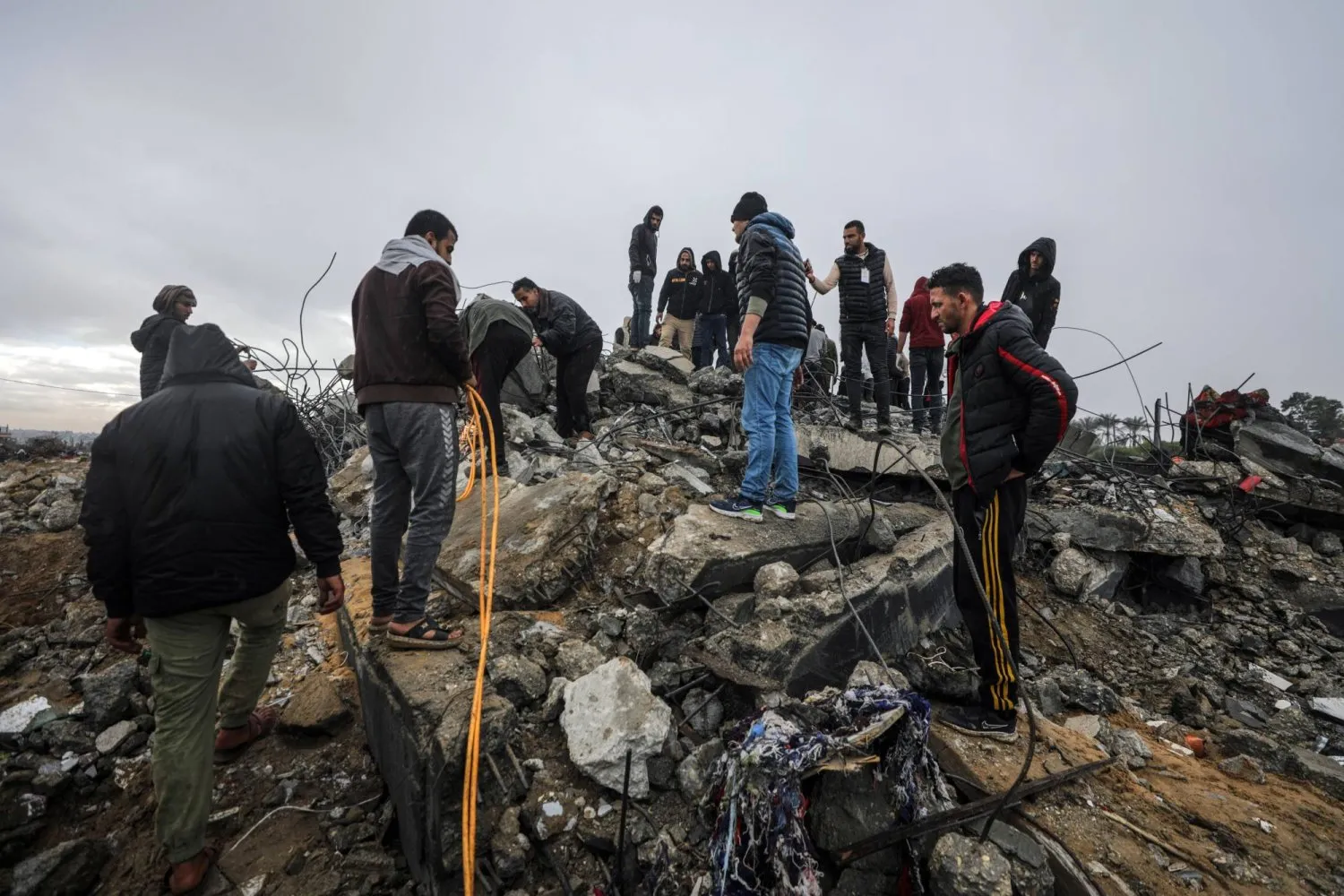 Filistinliler, İsrail'in 29 Ocak 2024'te Gazze Şeridi'ndeki Deyr el-Belah'a düzenlediği baskınların ardından yıkılan bir binanın enkazında arama yapıyor (AP)