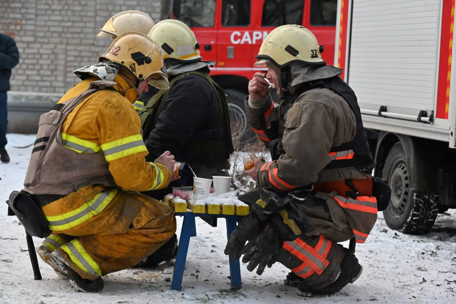 أفراد من الدفاع المدني يستريحون في موقع هجوم صاروخي على خاركيف (أ.ف.ب)