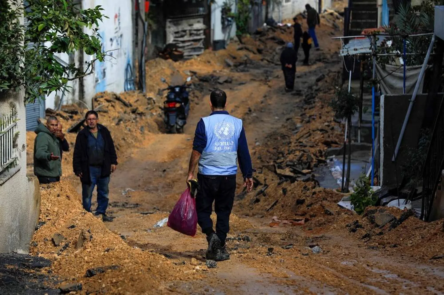 A man wearing a jacket of the UN agency for Palestinian refugees (UNWRA) walks on a street which has been bulldozed by the Israeli forces during a raid in Jenin in the occupied West Bank on January 29, 2024. (AFP)