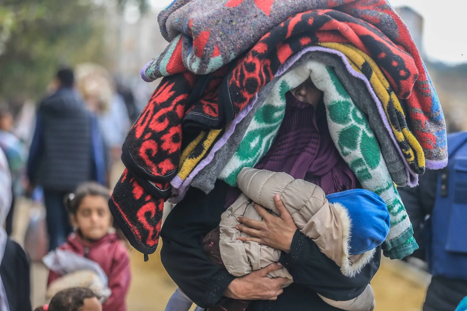سيدة فلسطينية تغادر المنطقة المحيطة بمستشفى الناصر في خان يونس حاملة طفلها وما استطاعت من أمتعة بعد أوامر إسرائيلية بإخلائها (د.ب.أ) 