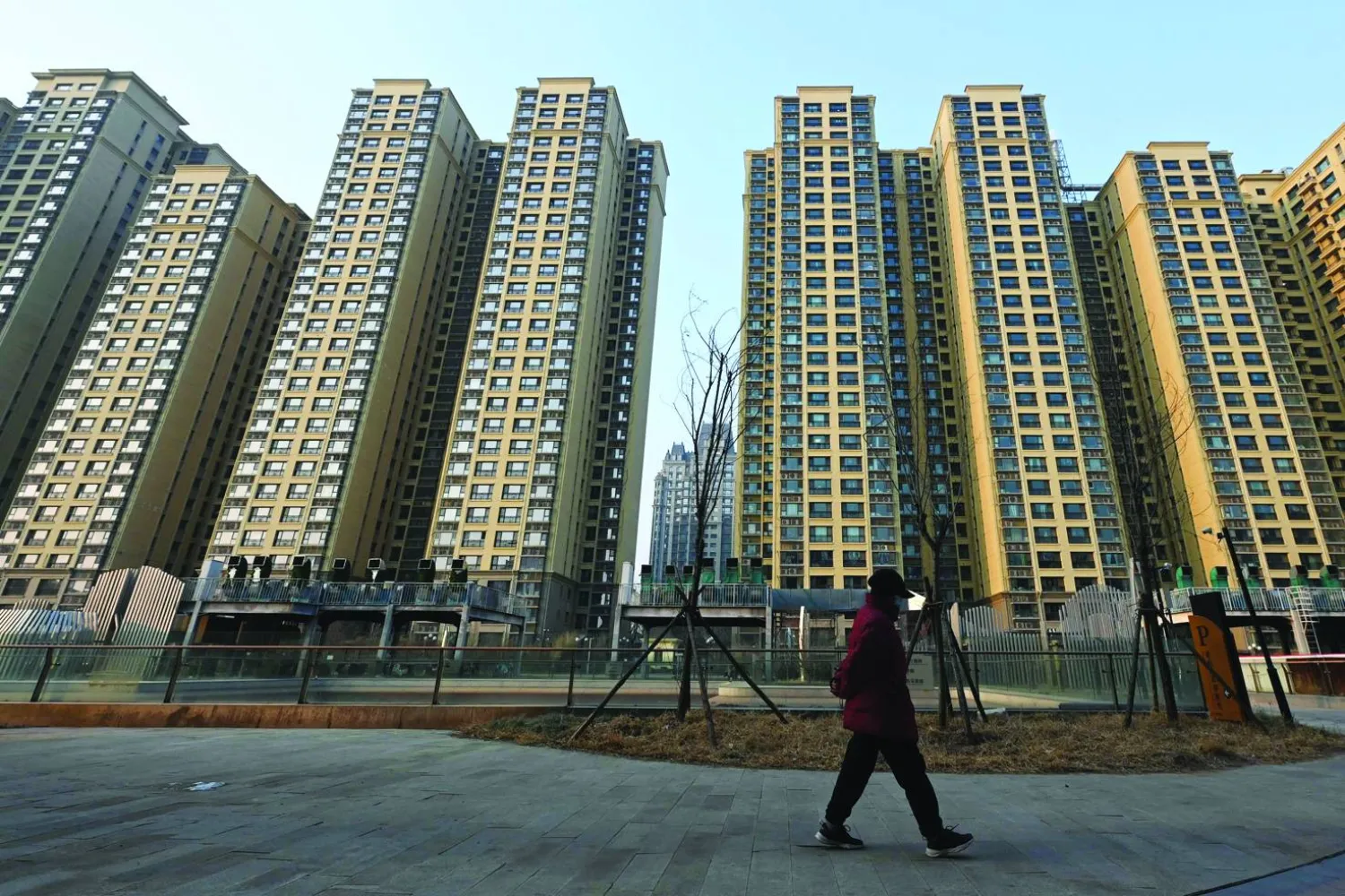 امرأة تسير بجوار مجمع سكني تابع لمجموعة «إيفرغراند» يسمى «قصر إيفرغراند» في بكين (أ.ف.ب)