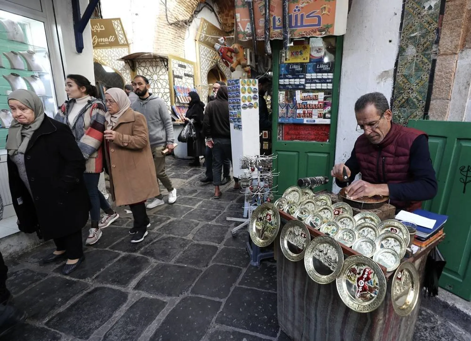 A Tunisian craftsman carves designs into a copper disk in the souk (open-air market) of the old city in Tunis, Tunisian, 17 January 2024. (EPA)
