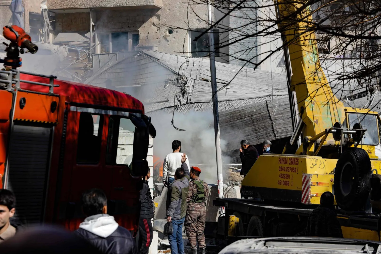 People and security forces gather in front of a building destroyed in a reported Israeli strike in Damascus on January 20, 2024. (Photo by Louai Beshara / AFP)