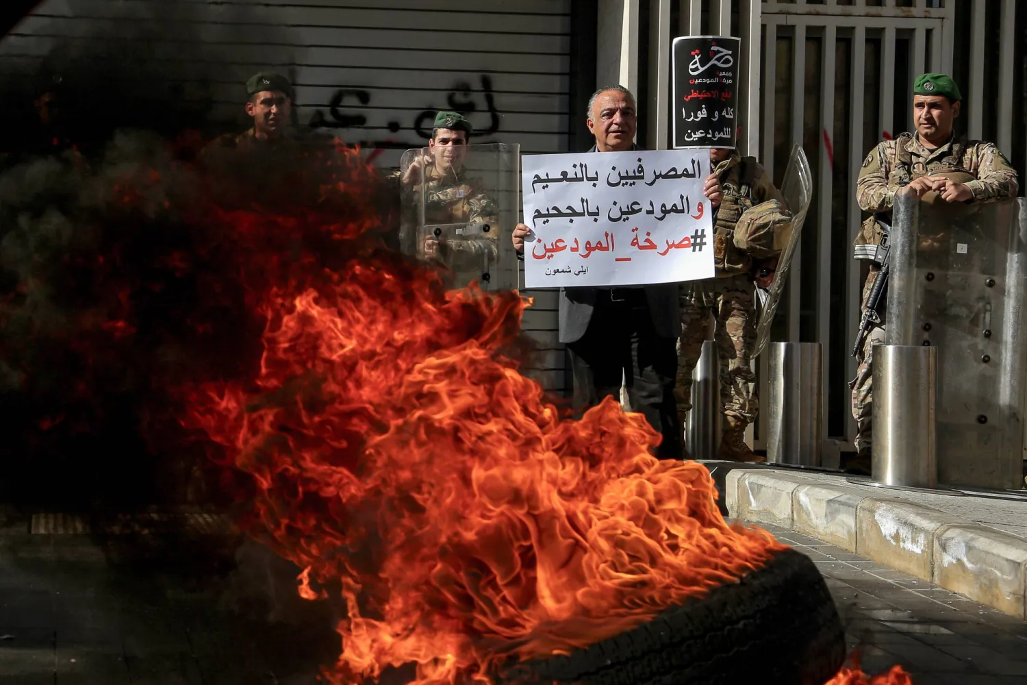 خلال احتجاجات للمودعين في لبنان للمطالبة باستعادة ودائعهم المحتجزة في المصارف ويرفع أحدهم لافتة كُتب عليها «المصرفيون يعيشون في الجنة والمودعون يعيشون في الجحيم» (د.ب.أ)