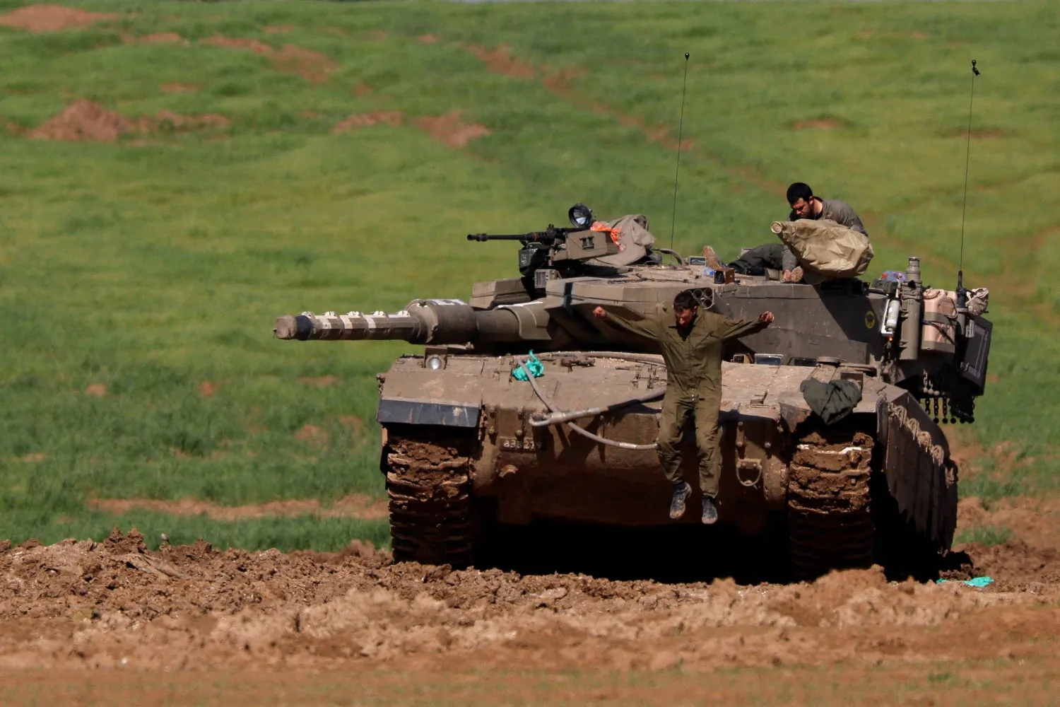 جندي إسرائيلي يقفز من دبابة بالقرب من الحدود مع شمال غزة (رويترز)