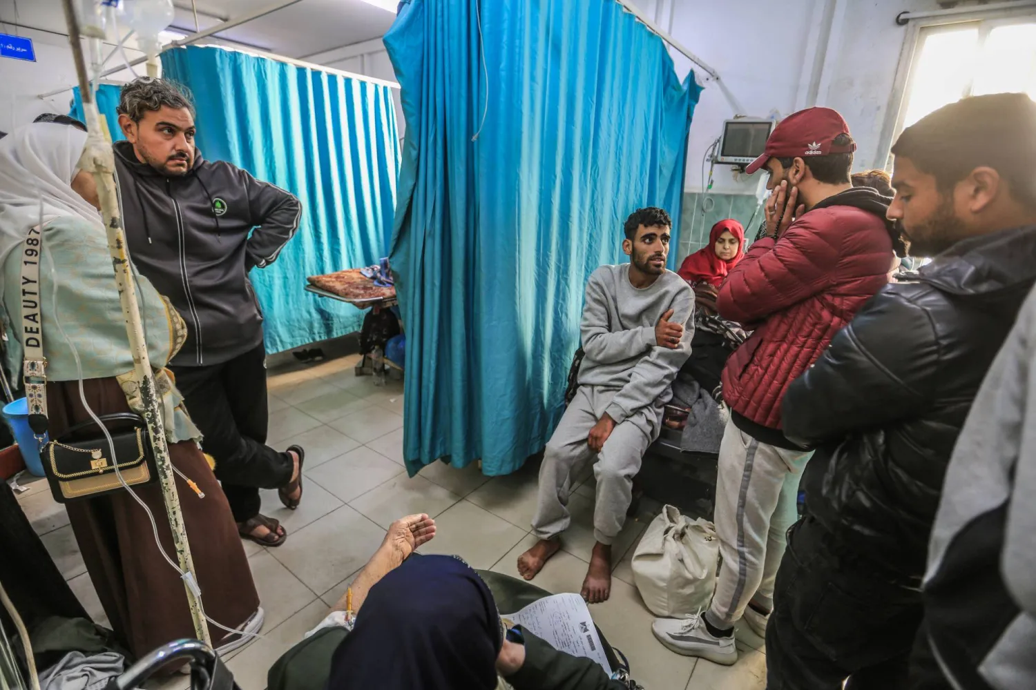 معتقل فلسطيني أُطلق سراحه (في الوسط) يتحدث مع أقاربه أثناء تواجده في مستشفى النجار برفح (د.ب.أ)