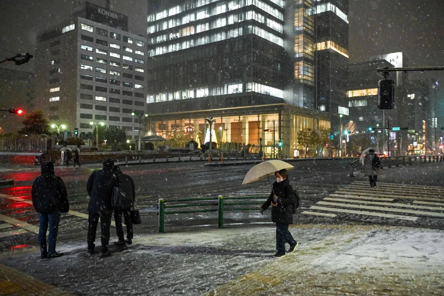 مشاة يسيرون على الثلوج في أحد شوارع العاصمة اليابانية طوكيو (أ.ف.ب)