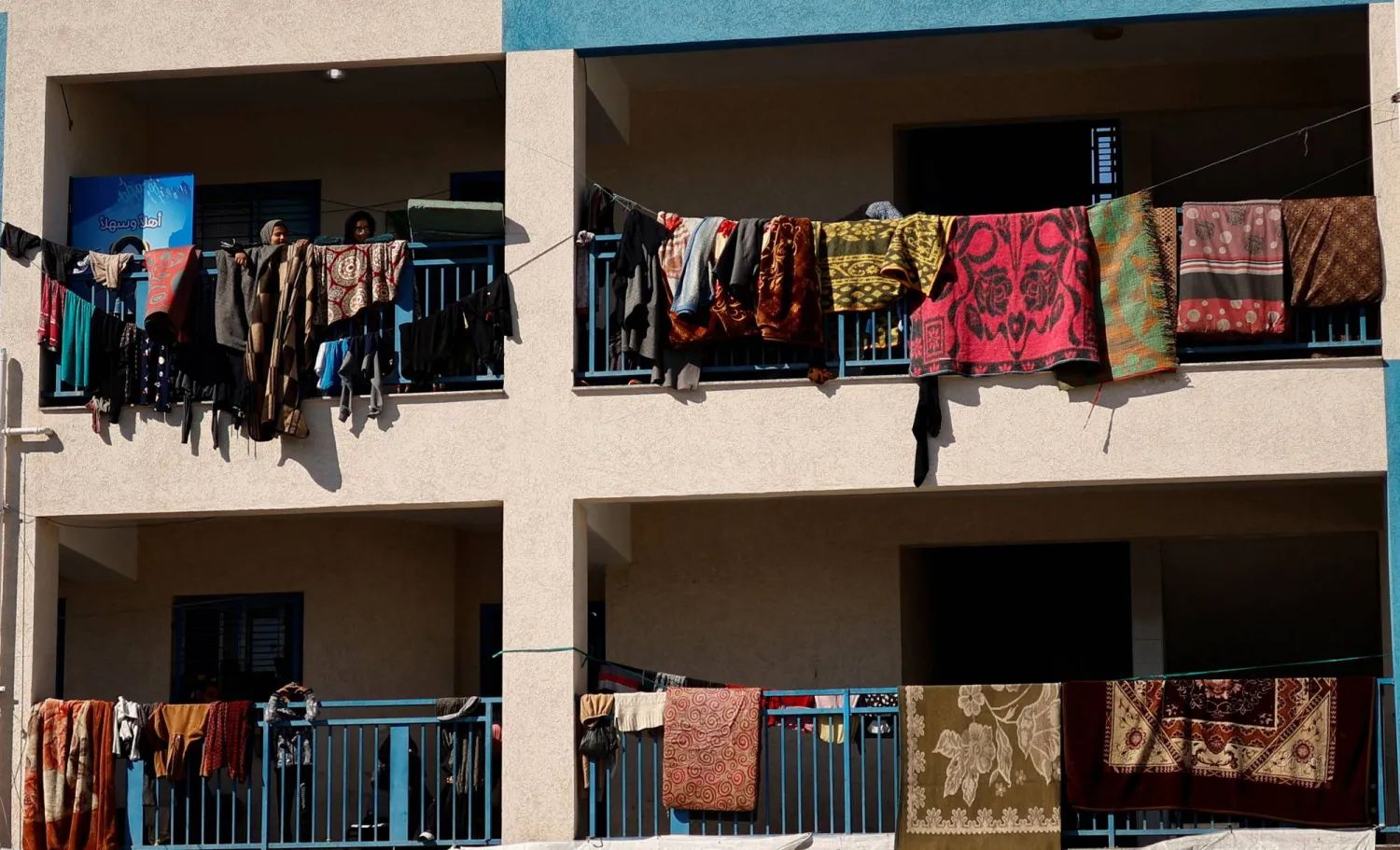 نازحون فلسطينيون يعلقون ملابسهم أثناء لجوئهم إلى مدرسة تابعة لـ«الأونروا» في رفح بجنوب قطاع غزة (رويترز)