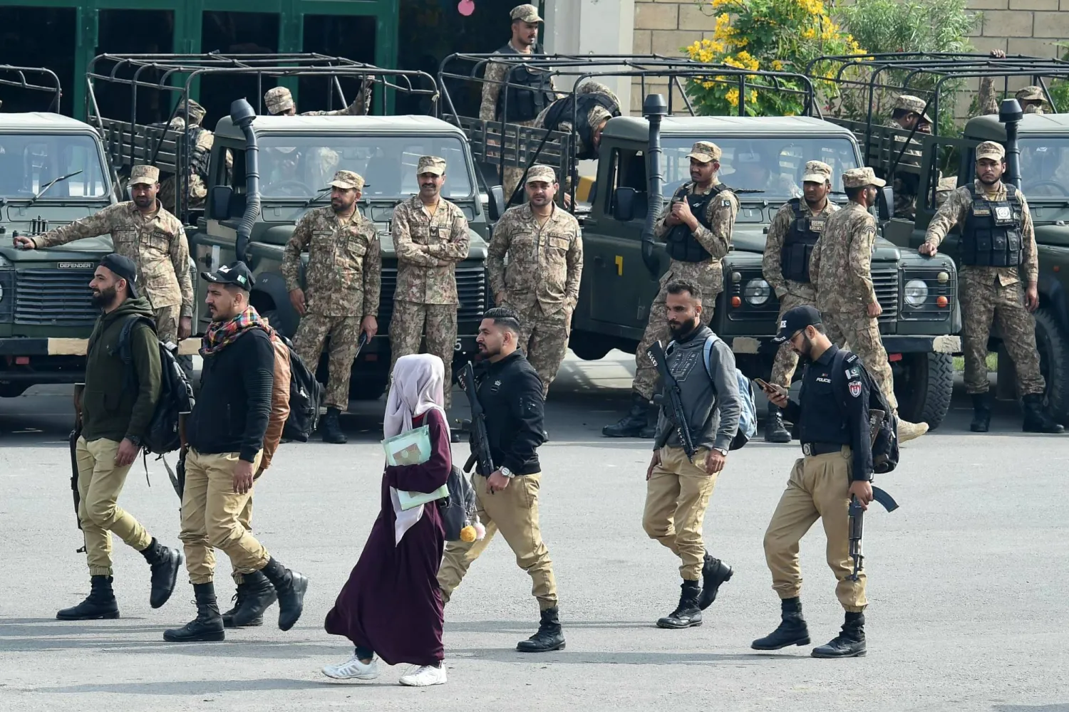 فتاة تسير أمام أفراد أمن بمركز توزيع المواد الانتخابية في كراتشي (أ.ف.ب)