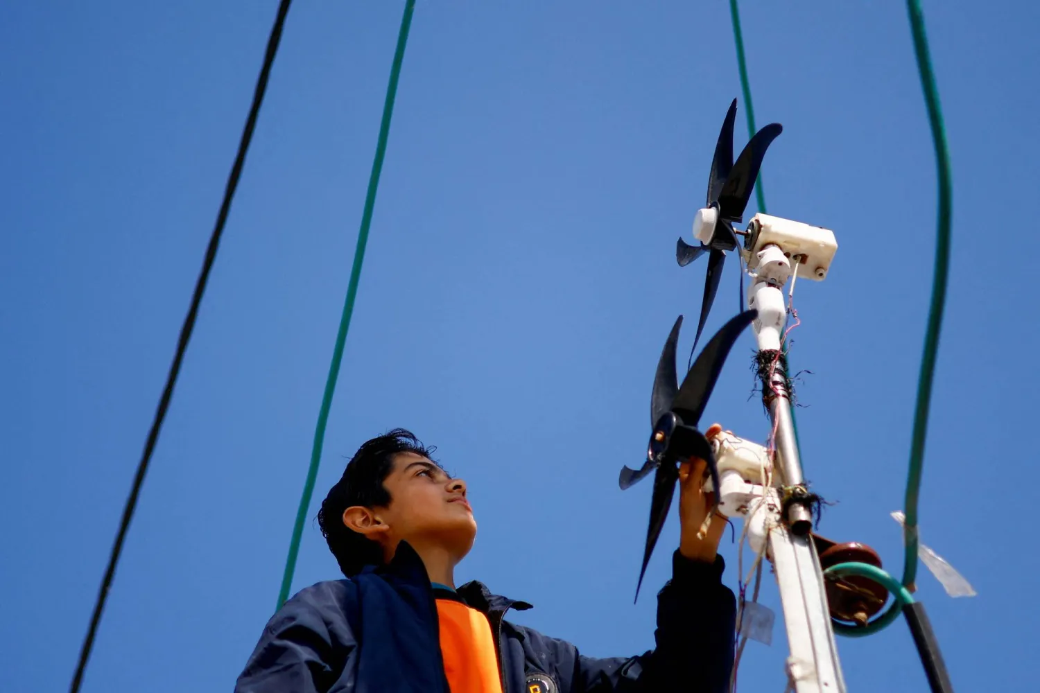 حسام العطار يراقب توربينات الرياح التي يستخدمها لإضاءة خيمة عائلته في رفح (رويترز)