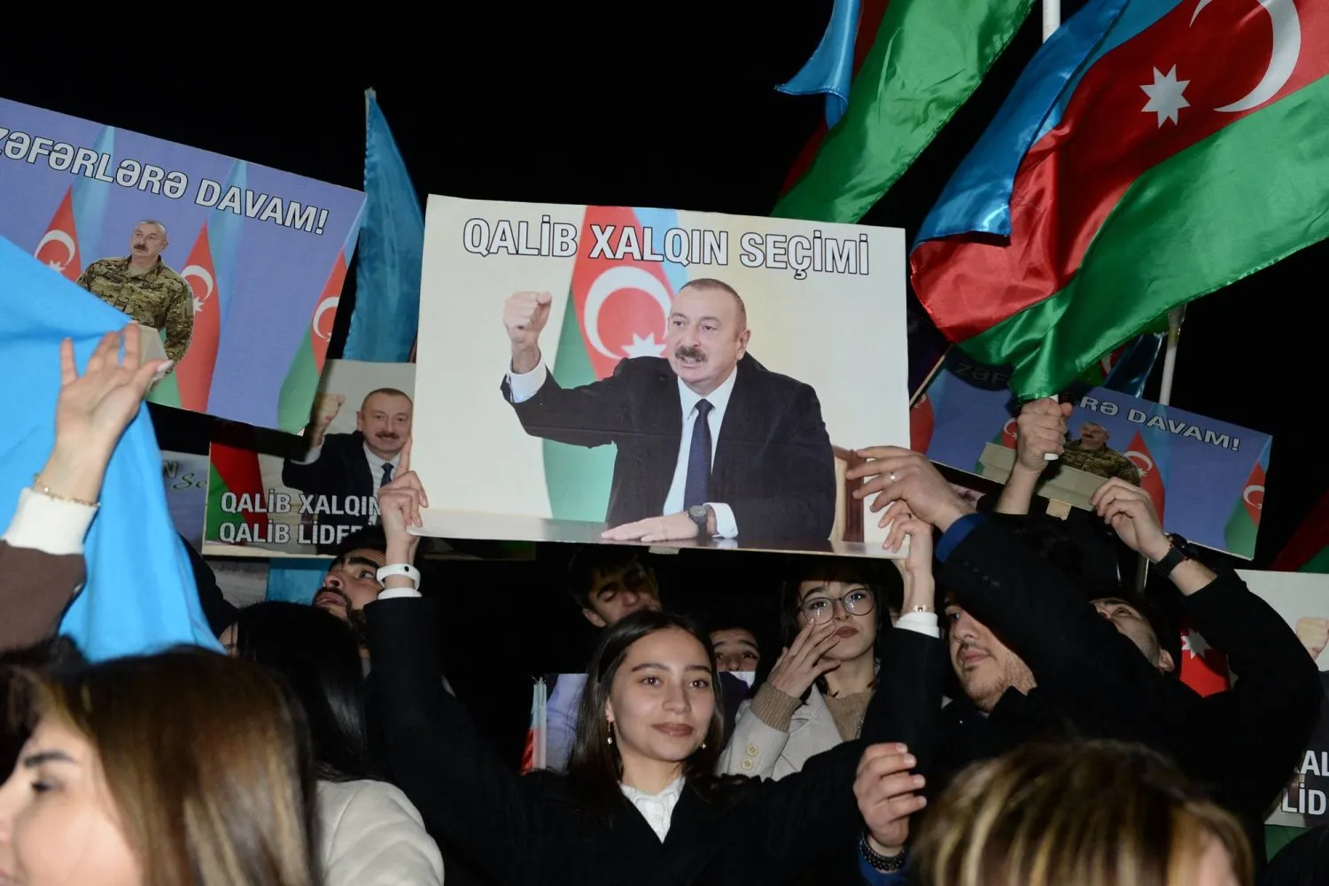 Cumhurbaşkanlığı seçimlerinde sandıklar kapandıktan sonra destekçileri İlham Aliyev'in resimlerini ve Azerbaycan bayrağını kaldırıyor (AFP)