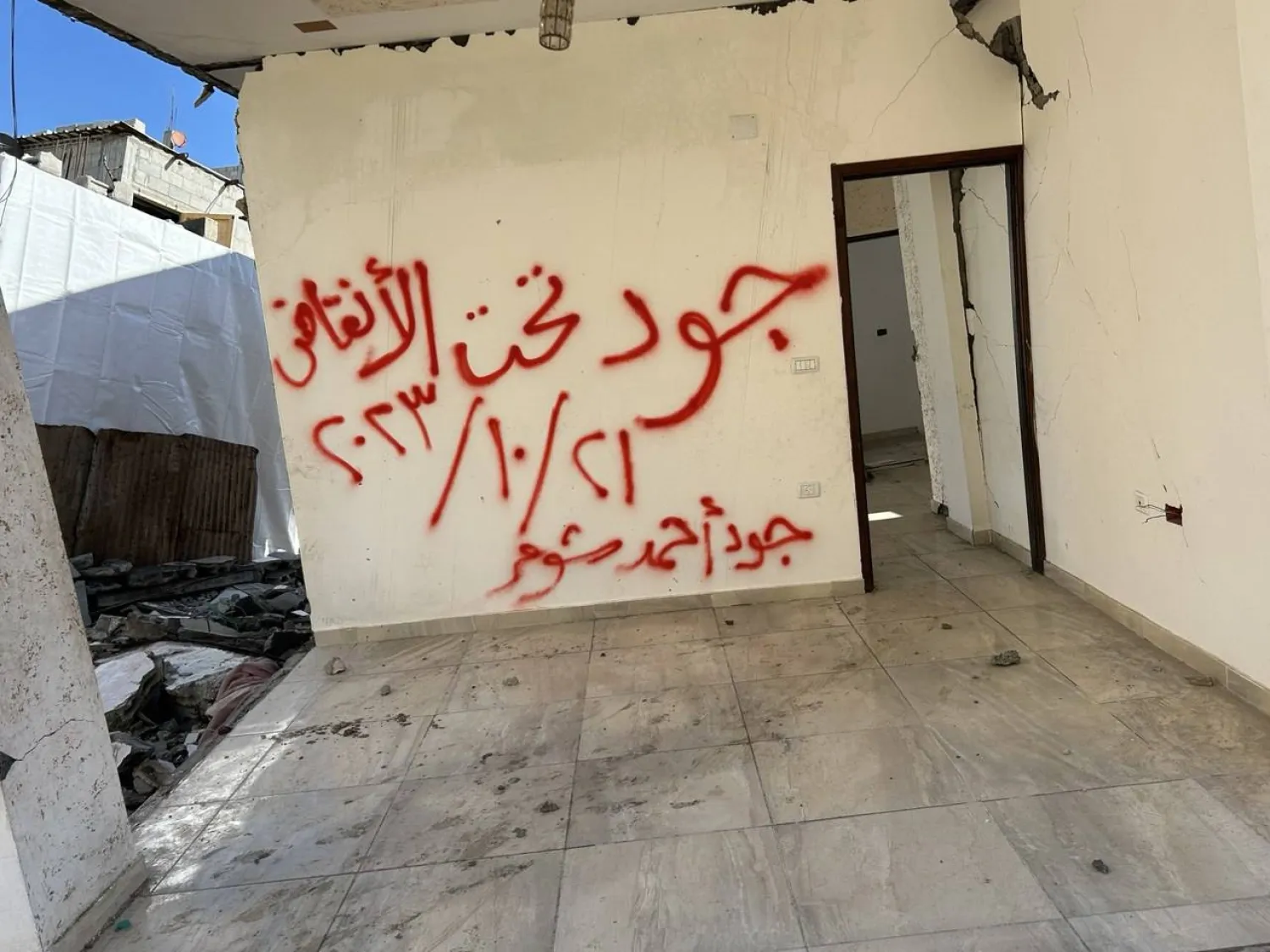 «جود تحت الأنقاض» عبارة خُطَّت بلون أحمر على جدران منزل تعرض لقصف إسرائيلي في دير البلح (وكالة أنباء العالم العربي)