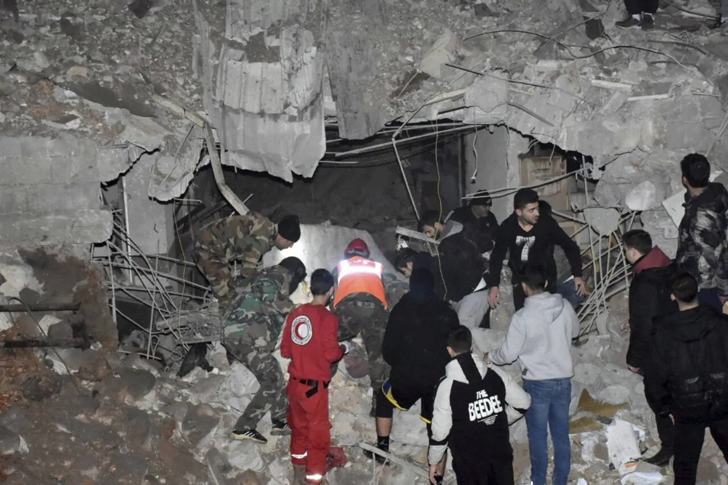Güvenlik güçleri ve sivil savunma çalışanları, çarşamba günü şafak vakti İsrail’in Suriye’nin Humus kentindeki saldırılarında yıkılan bir binanın enkazı altında kurbanları arıyor (AFP)