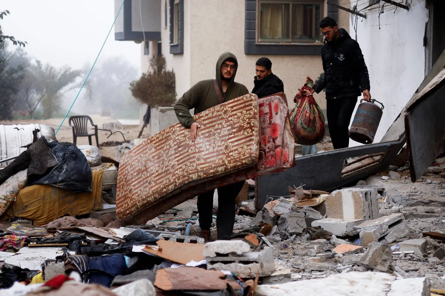 Palestinians carry belongings at the site of an Israeli strike on a house in Rafah in the southern Gaza Strip, February 9, 2024. REUTERS/Ibraheem Abu Mustafa