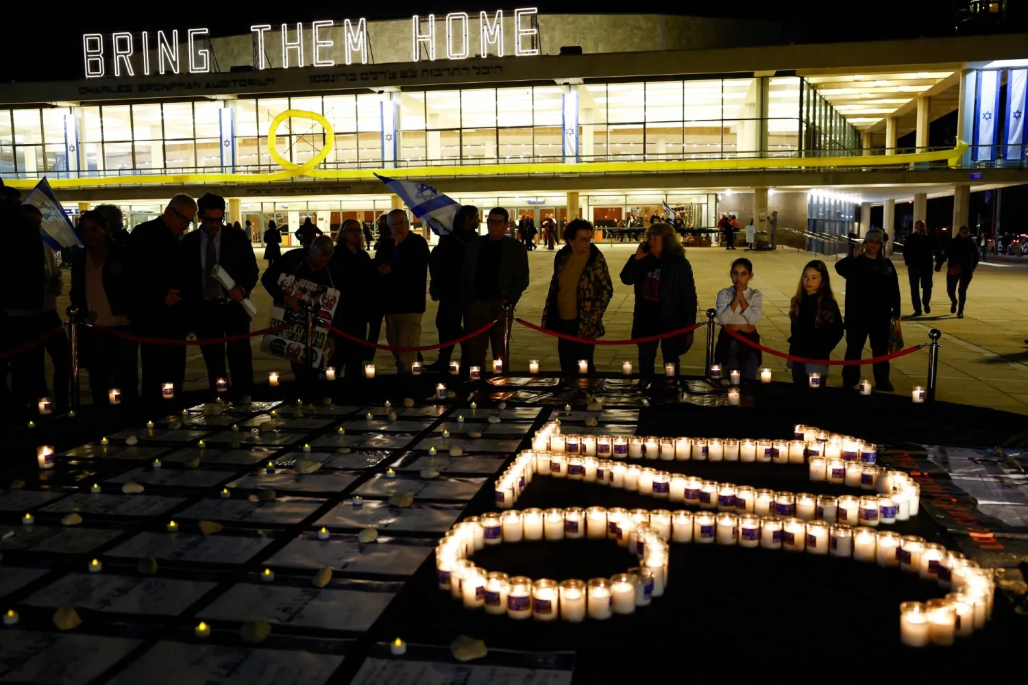 People look at an installation with candles which makes out the number of days the hostages have been captive since October 7, as people begin to gather for a protest against Israeli Prime Minister Benjamin Netanyahu's government, at Habima Square in Tel Aviv, Israel, February 10, 2024. REUTERS/Susana Vera