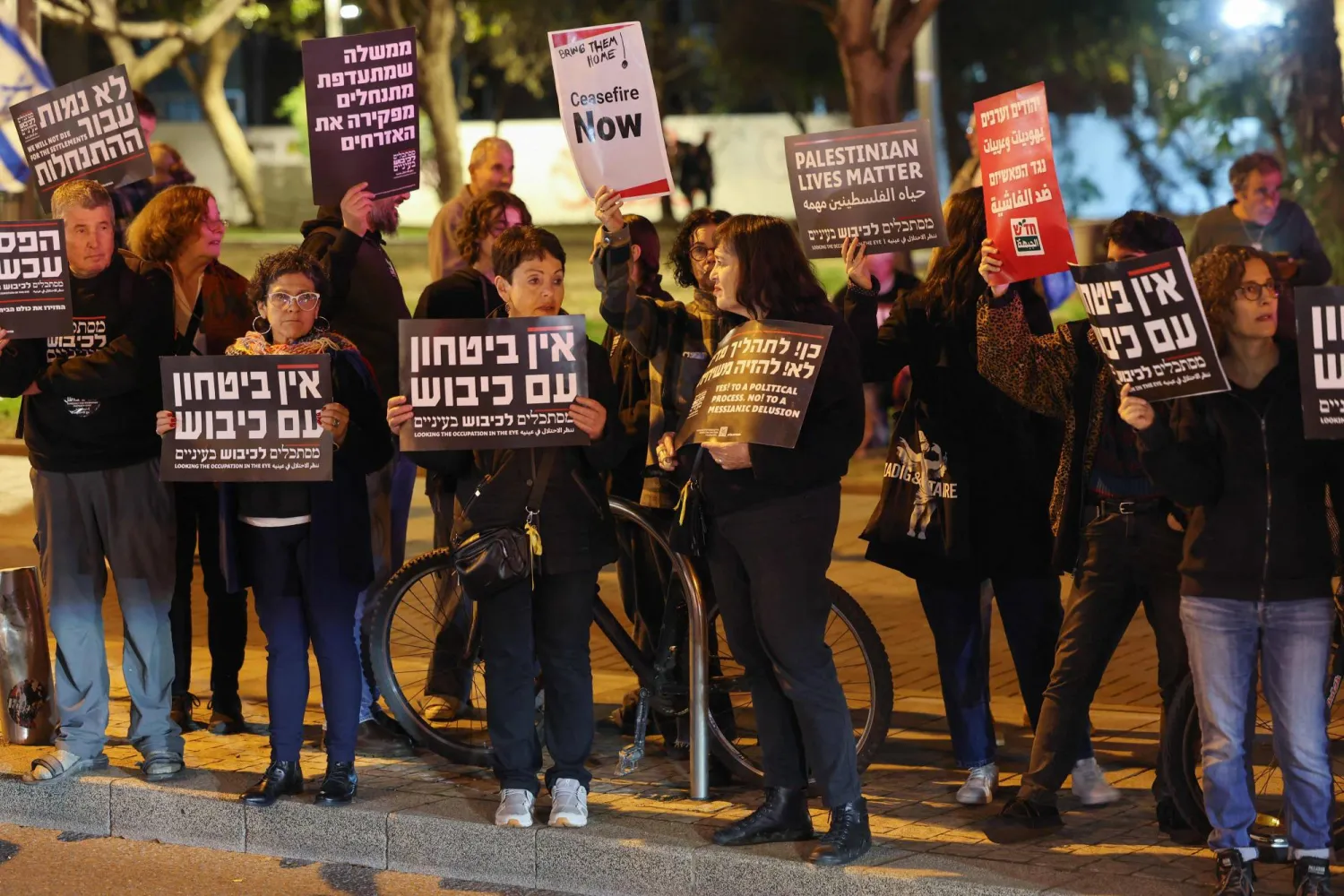 نشطاء يساريون إسرائيليون يرفعون لافتات أثناء تظاهرهم ضد الحرب في غزة خارج وزارة الدفاع في تل أبيب (أ.ف.ب)