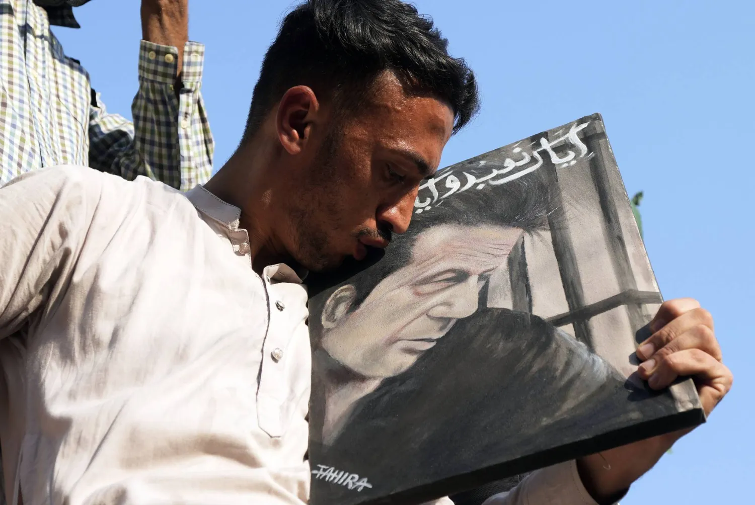 أحد مؤيدي رئيس الوزراء الباكستاني السابق المسجون عمران خان يقبل صورة زعيمه خلال احتجاج أمام لجنة الانتخابات الباكستانية في كراتشي (أ.ب)