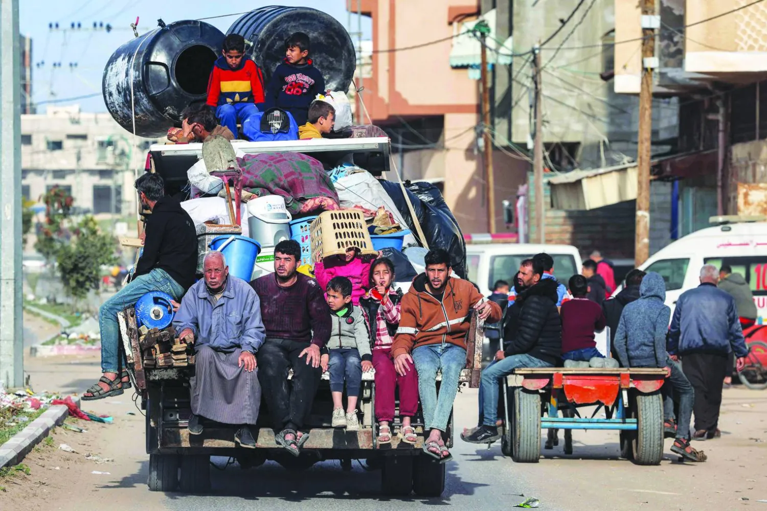 Members of a Palestinian family ride in the back of a truck with belongings as they flee Rafah in the southern Gaza Strip taking the coastal road north towards the central Gaza Strip on February 12, 2024 amid the ongoing conflict there between Israel and the Palestinian group Hamas. (Photo by MOHAMMED ABED / AFP)

