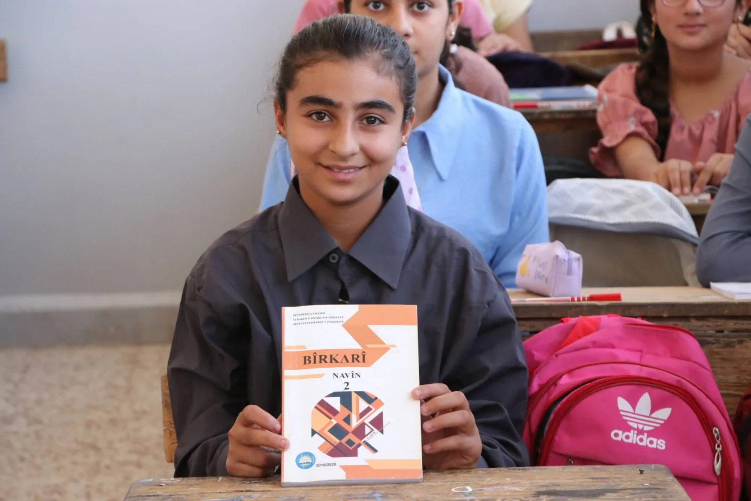 الطالبة مزكين دلو تمسك كتاب الرياضيات بعد ترجمته إلى لغتها الأم الكردية (الشرق الأوسط)