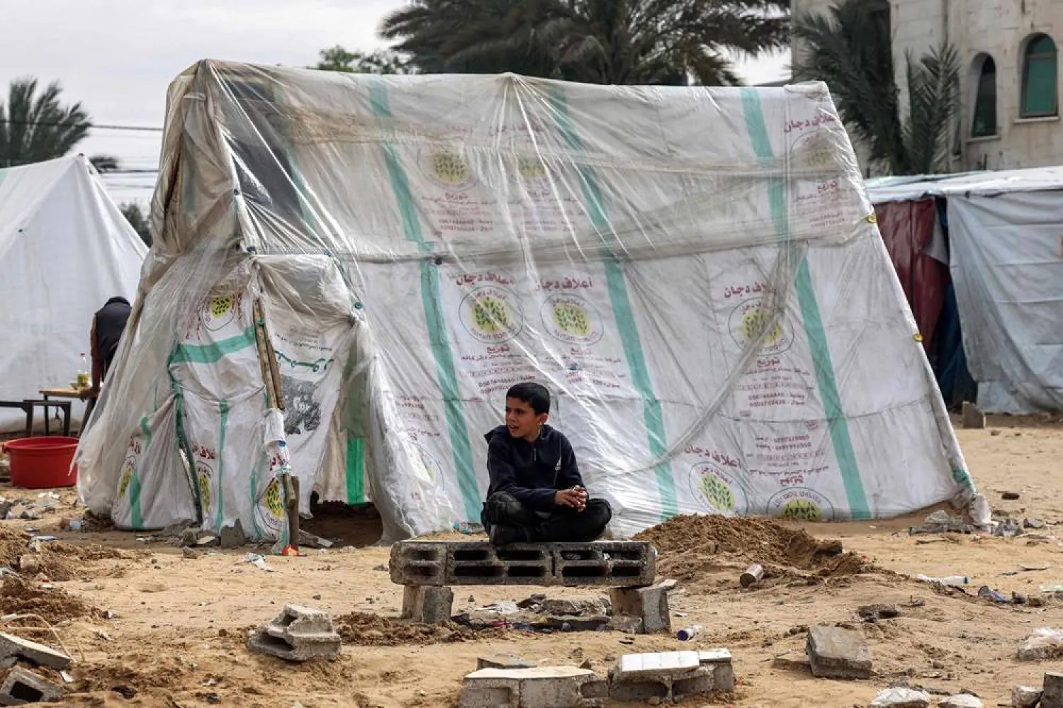  A Palestinian boy sits near a tent for displaced people in Rafah, in the southern Gaza Strip, on February 13, 2024, amid the ongoing conflict between Israel and the Palestinian group Hamas. (AFP) 