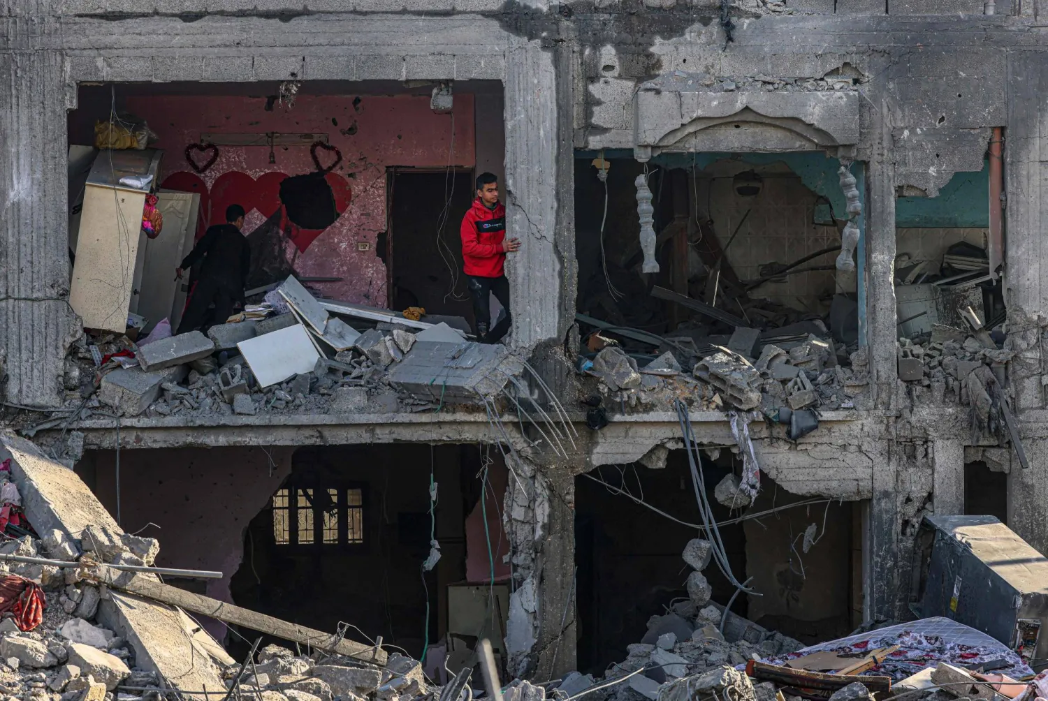 Palestinians inspect the damage in the rubble of a building where two hostages were reportedly held before being rescued during an operation by Israeli security forces in Rafah, on the southern Gaza Strip on February 12, 2024, amid ongoing battles between Israel and the group Hamas. (Photo by SAID KHATIB / AFP)