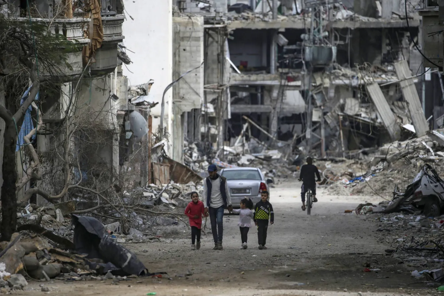 عائلة فلسطينية تمر أمام المنازل المدمرة خلال عملية عسكرية إسرائيلية في جنوب قطاع غزة (إ.ب.أ)