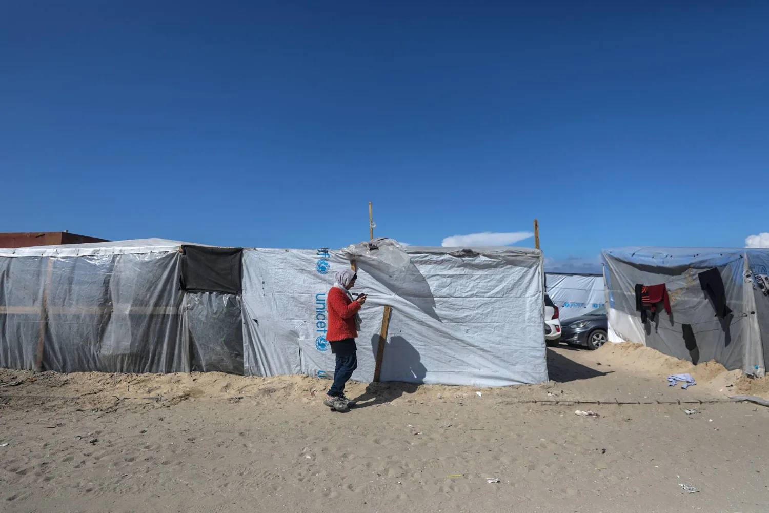 فتاة فلسطينية نازحة مع عائلتها من رفح تسير خارج ملجأها في دير البلح، جنوب قطاع غزة، 14 فبراير 2024 (إ.ب.أ)