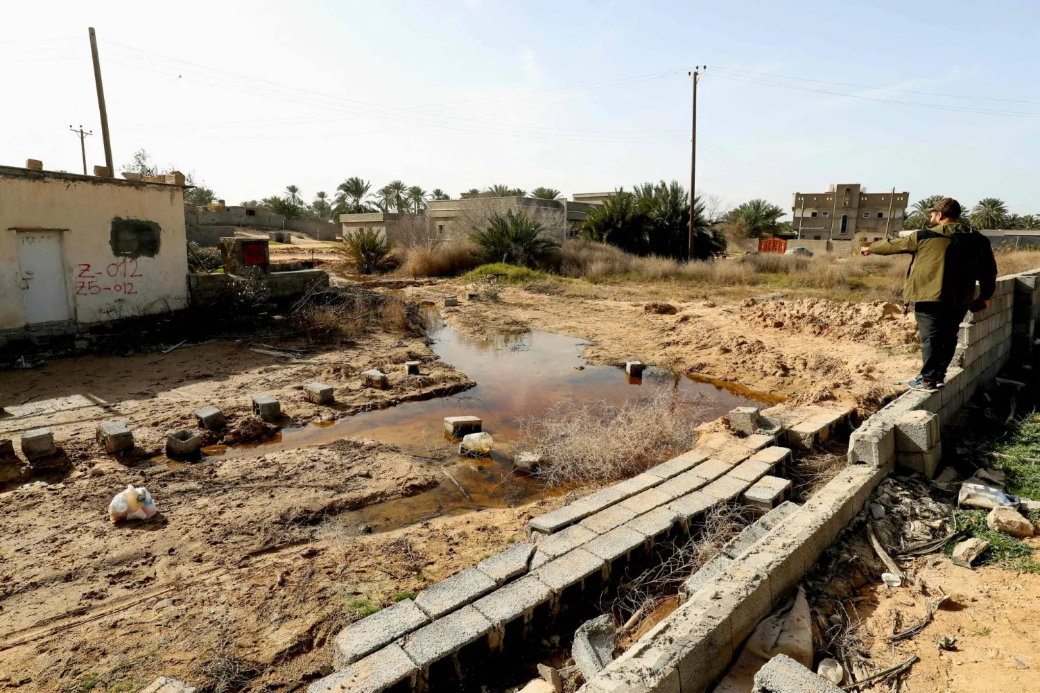 A man points at a flooded plot of land in Libya's coastal city of Zliten, 150 kilometres east of the capital on February 13, 2024, as a result of rising groundwater levels. (Photo by Mahmud Turkia / AFP)