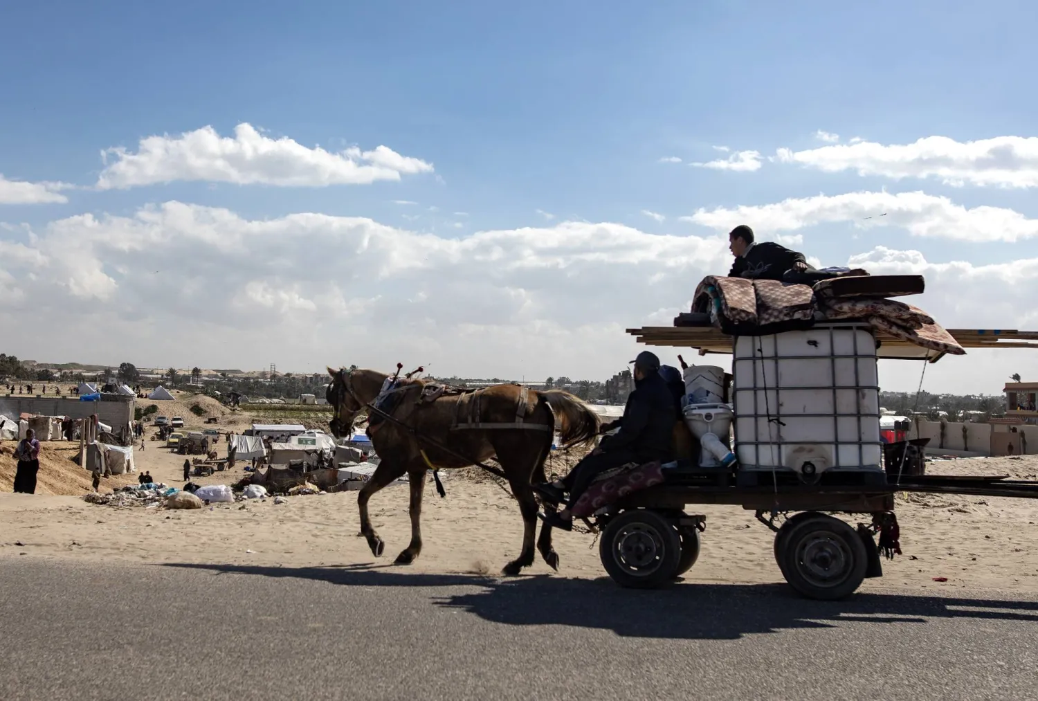 نازحون فلسطينيون يجلسون مع أمتعتهم على عربة يستعدون لمغادرة مخيم رفح جنوب قطاع غزة متجهين نحو الجزء الأوسط منه بعد إعلان الجيش الإسرائيلي عن إطلاق عملية عسكرية مرتقبة داخل رفح في 14 فبراير 2024 (إ.ب.أ)