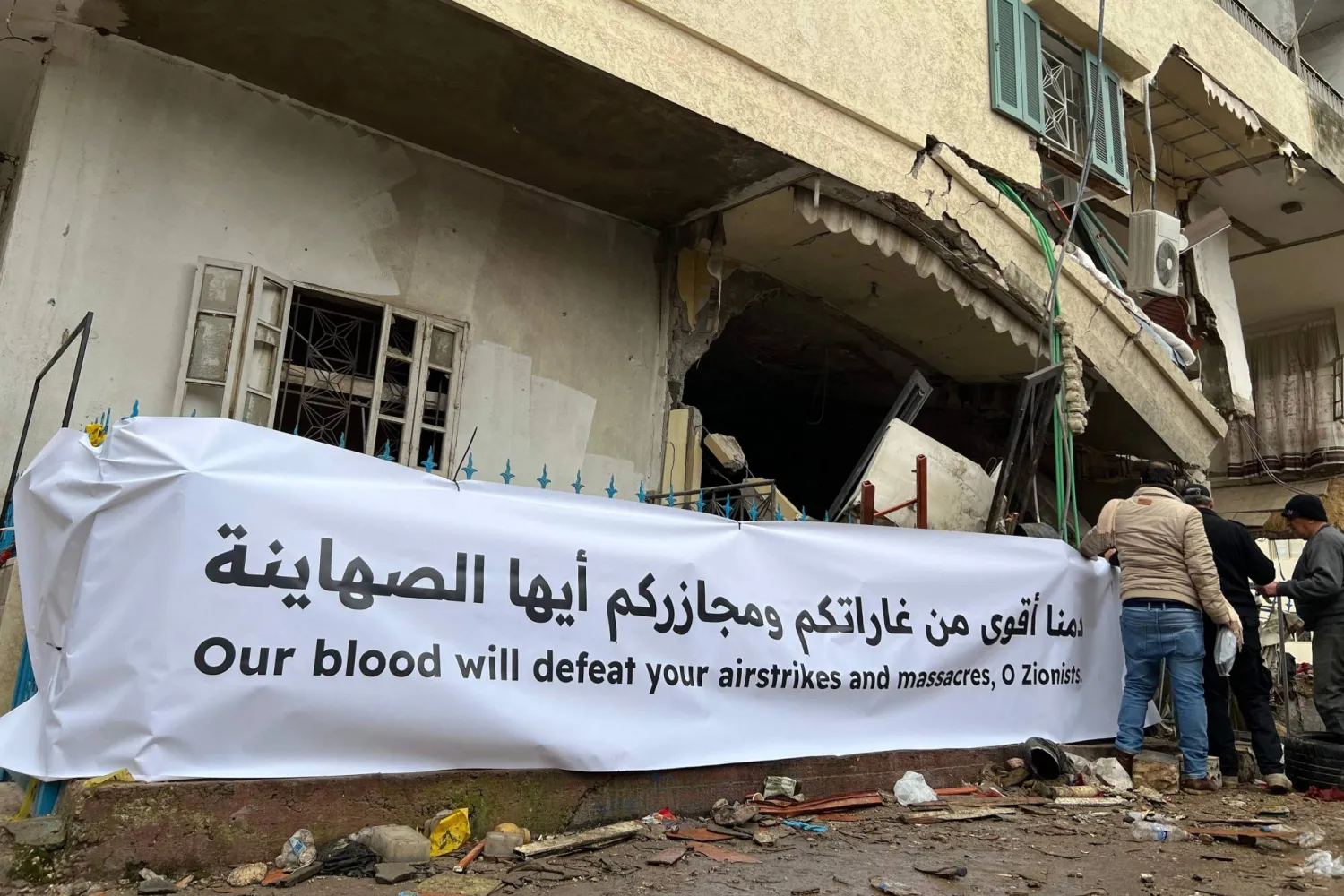 لبنانيون يقفون أمام مبنى دمره القصف الإسرائيلي في النبطية بجنوب لبنان (أ.ف.ب)