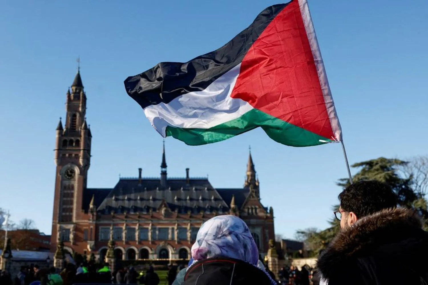 Protesters hold a Palestinian flag as they gather outside the International Court of Justice (ICJ) as judges rule on emergency measures against Israel following accusations by South Africa that the Israeli military operation in Gaza is a state-led genocide, in The Hague, Netherlands, January 26, 2024. (Reuters)