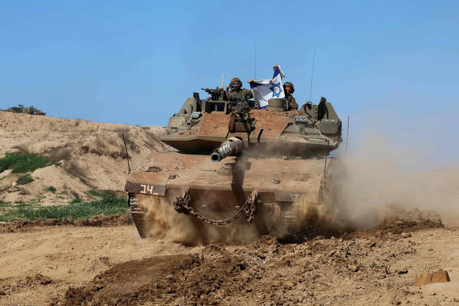 جنود إسرائيليون يرفعون العلم الوطني أثناء تحركهم على طول الحدود مع غزة (أ.ف.ب)