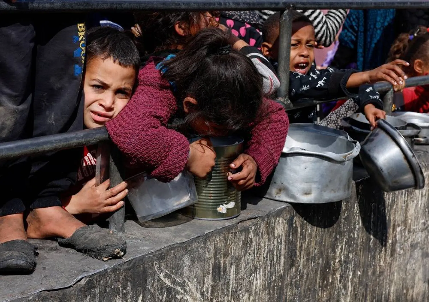  Palestinian children wait to receive food cooked by a charity kitchen amid shortages of food supplies, as the ongoing conflict between Israel and the Palestinian group Hamas continues, in Rafah, in the southern Gaza Strip, February 20, 2024. (Reuters)