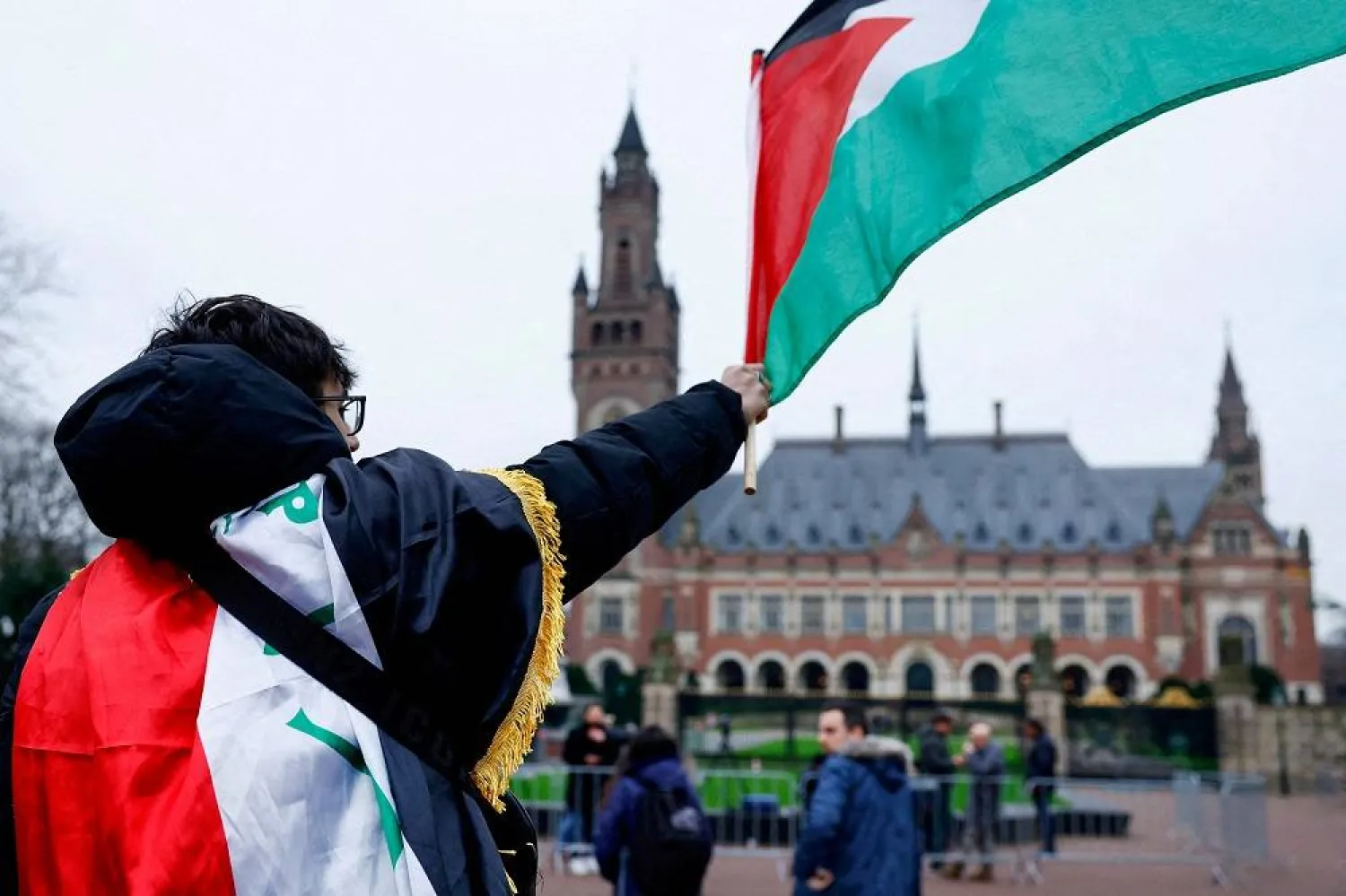 A man waves a Palestinian flag as people protest on the day of a public hearing held by the International Court of Justice (ICJ) to allow parties to give their views on the legal consequences of Israel's occupation of Palestinian territories before eventually issuing a non-binding legal opinion, in The Hague, Netherlands, February 21, 2024. (Reuters) 