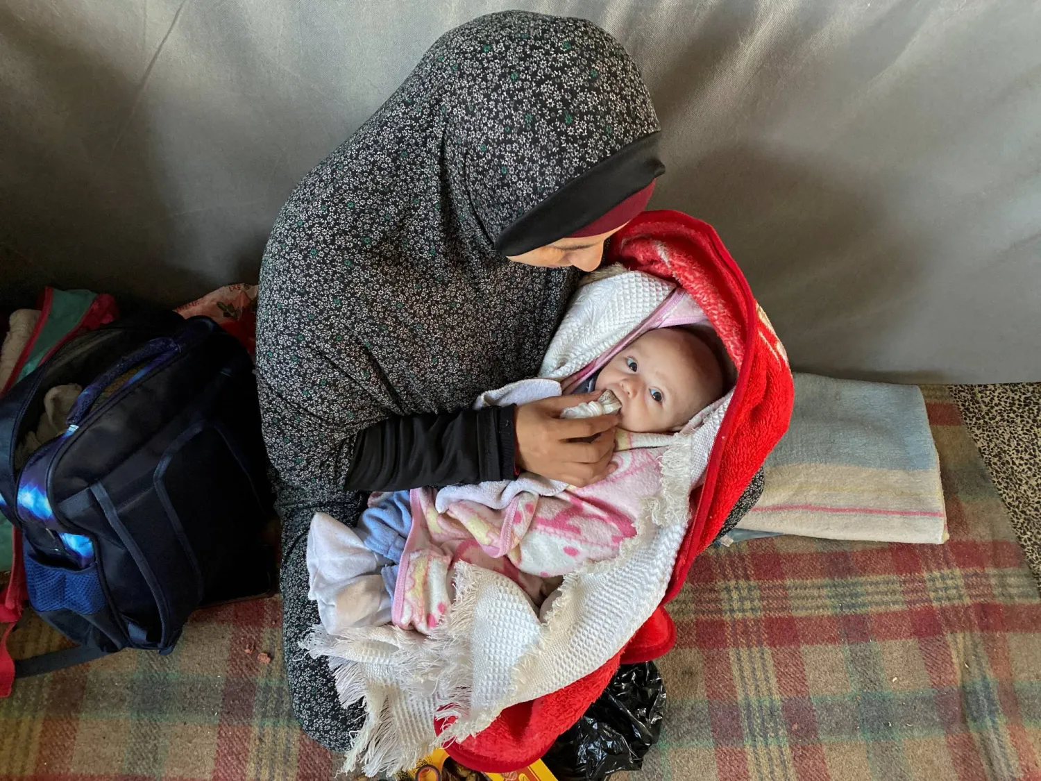 Palestinian woman Warda Mattar feeds her newborn dates, instead of milk, amidst food scarcity and lack of milk, at a school where they shelter in Nuseirat in the central Gaza Strip February 25, 2024. REUTERS/Doaa Ruqqa